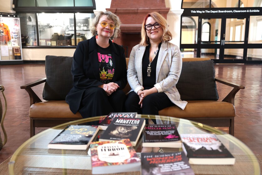 Two authors sit together in front of their books