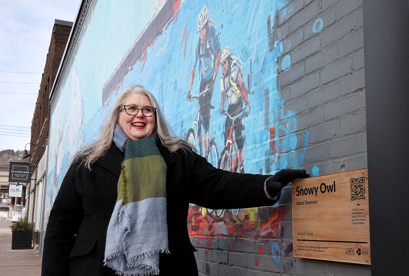 Woman stands by mural. 