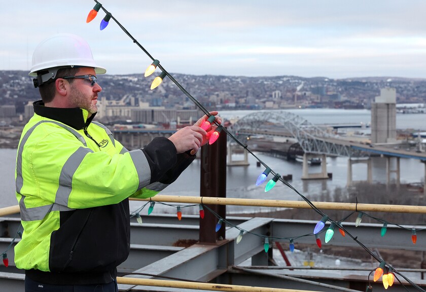 Man looks at lightbulbs high above bridge. 